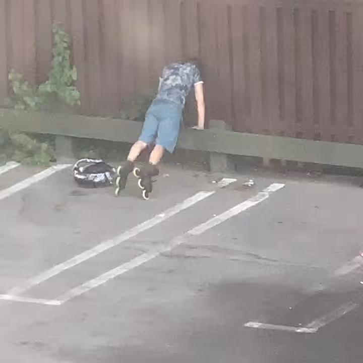 Boy Doing Push-ups on Rollerblades in Parking Lot