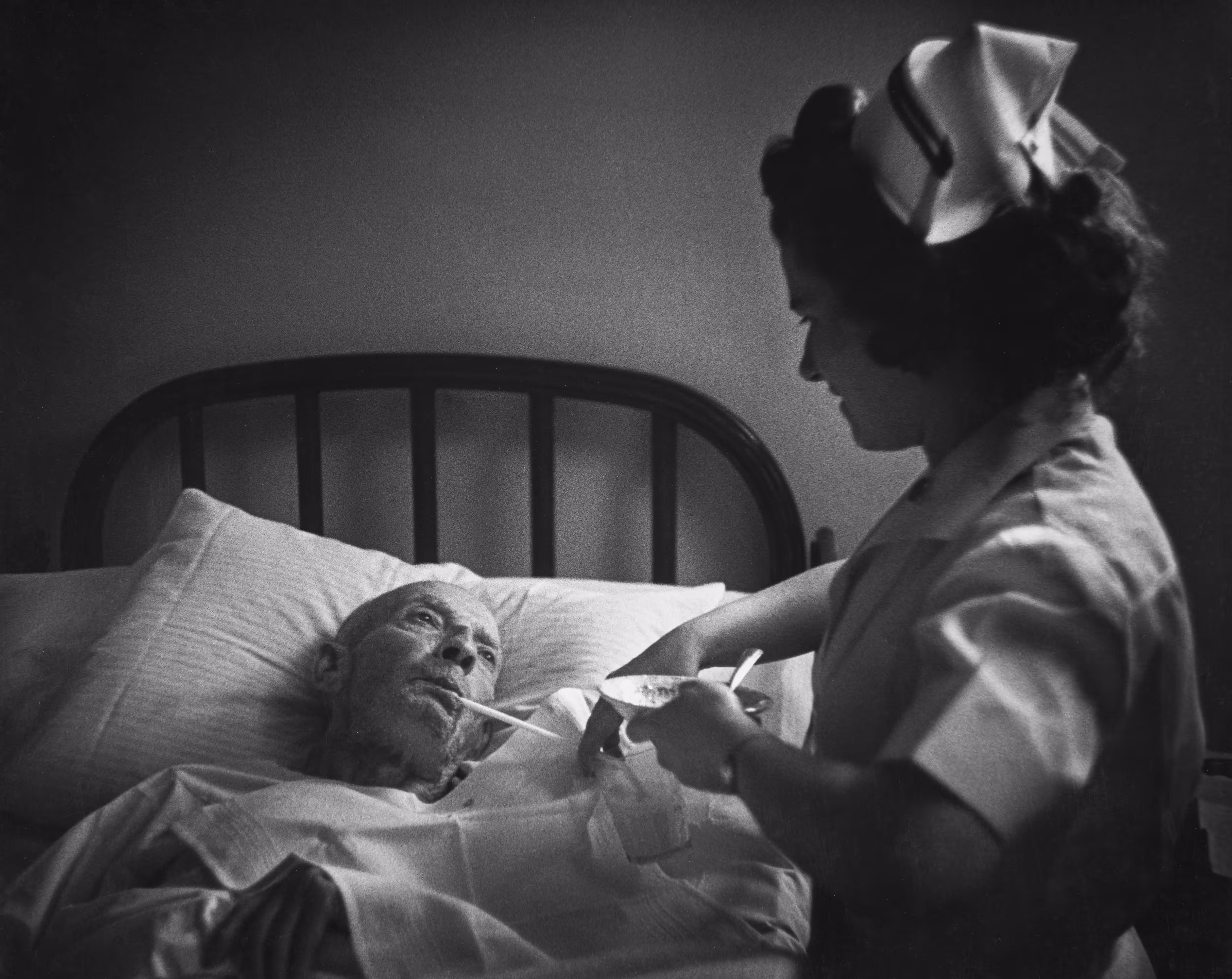 Country Doctor - Nurse Feeding Elderly Man with Straw as He Awaits Amputation of Foot