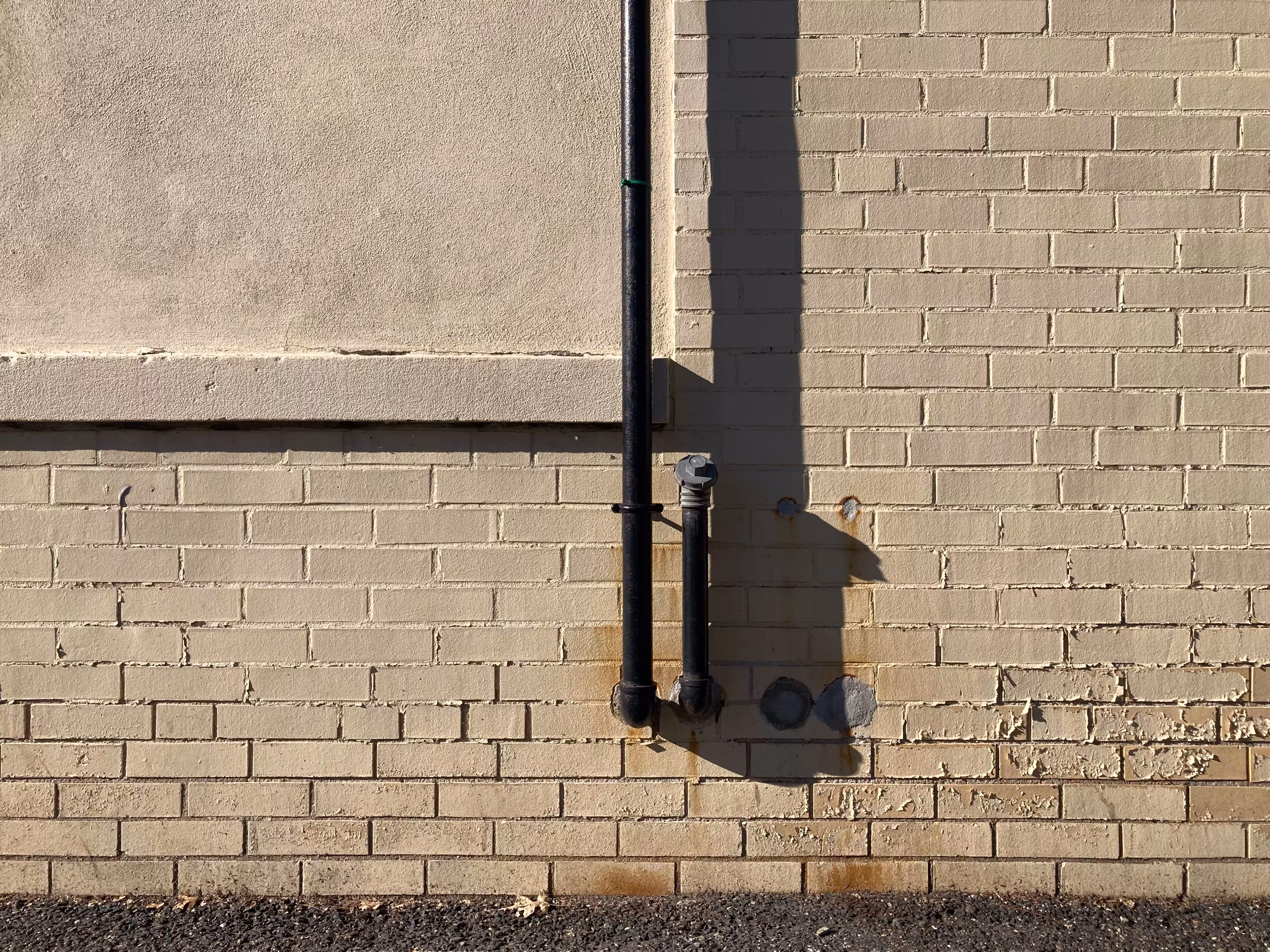morning light on a pipe casts a shadow on a wall and is content