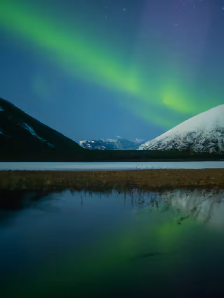 Northern Lights Over Snow Capped Mountain Lake