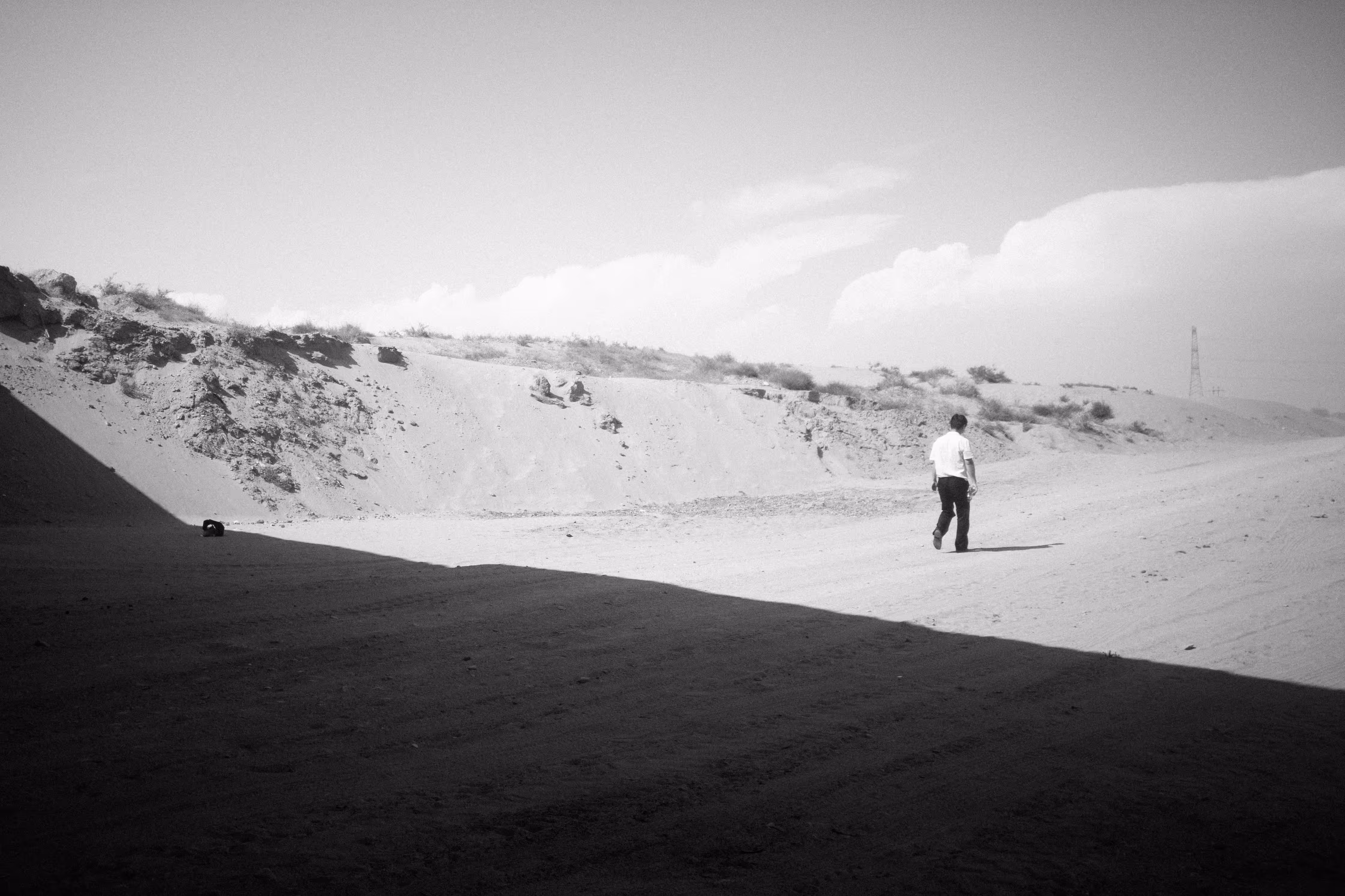 a man in a shirt walking down a dirt road on the edge of Taklamakan Desert
