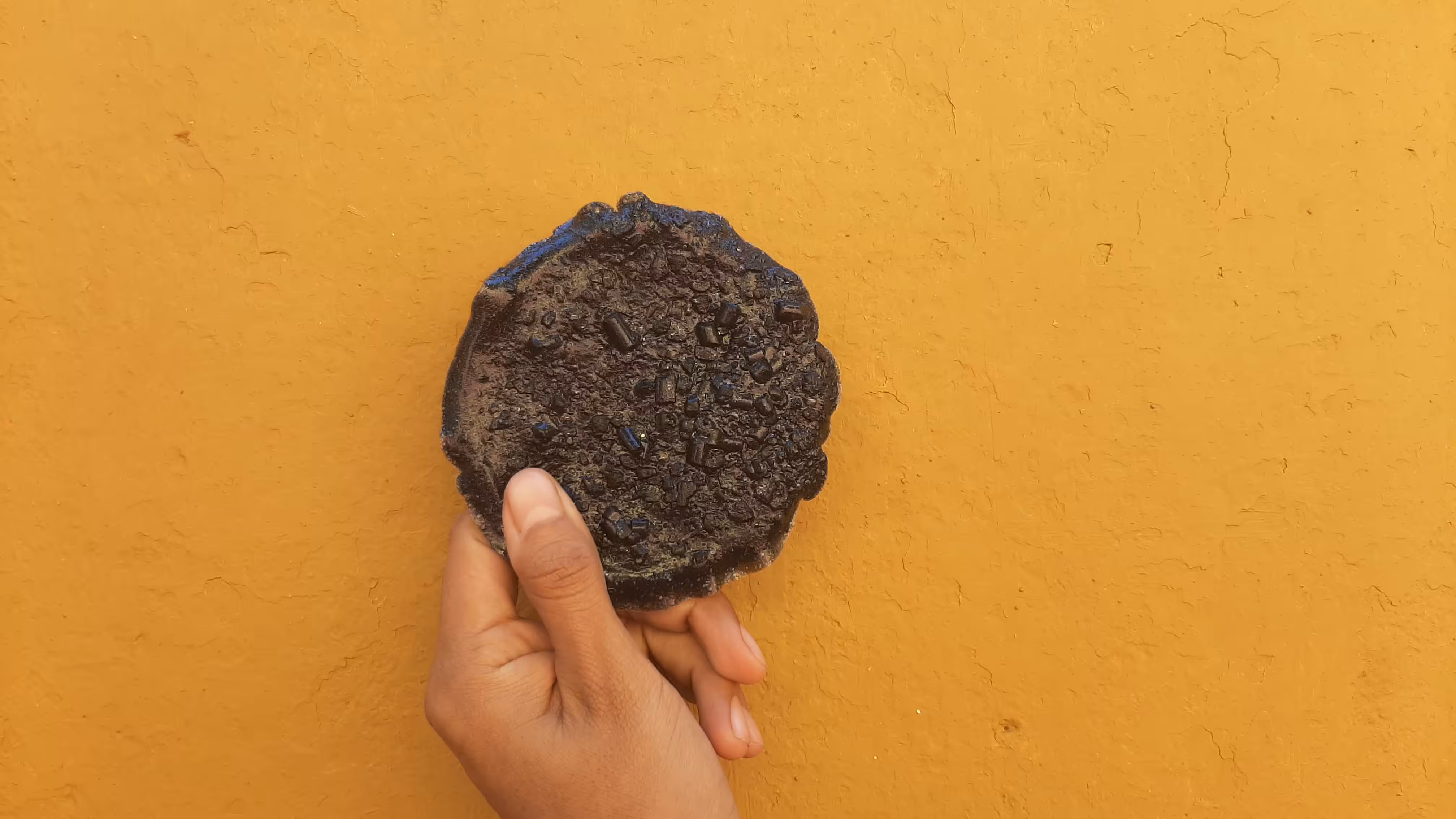 Circular shape, against a wall, held in my hand, back view