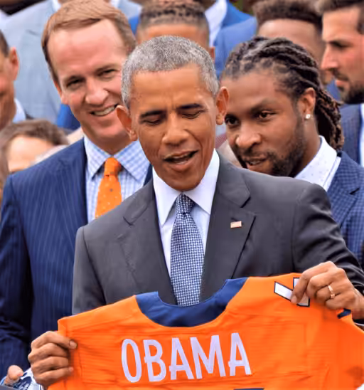 Peyton Manning watches President Barack Obama as he makes a joke honouring the Denver Broncos White